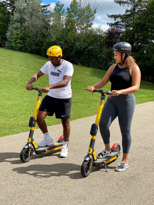 two people wearing helmets riding SCOOTY scooters